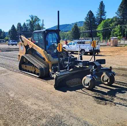 Skid steer with grading attachment leveling gravel
