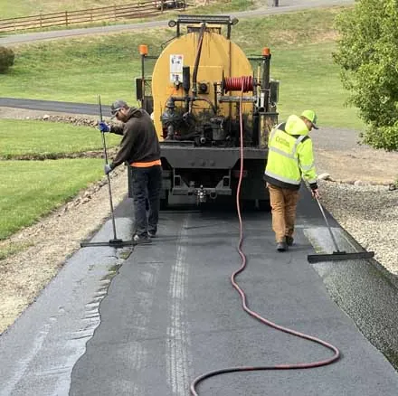 Crew squeegeeing sealcoat from a distributor truck